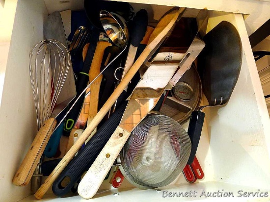 Kitchen utensils including tongs, spatulas, strainer, wooden spoons, whisk, lots more.