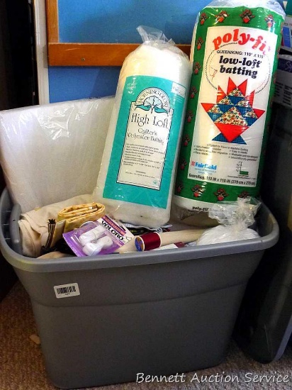 18 gallon tote filled with batting, material, velcro, bias tape, more. Three rolls of batting appear