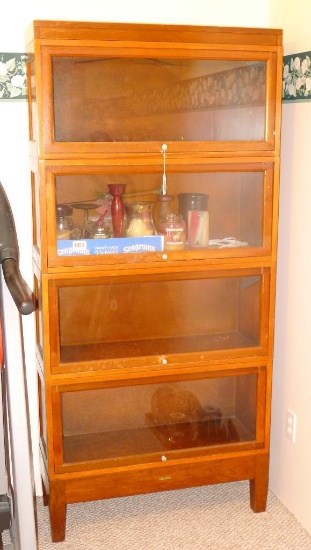 Vintage storage cabinet is framed in wood with glass doors that lift up and push in for access to
