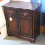 Wooden storage cabinet has 2 doors with 2 shelf storage inside. Measures 28