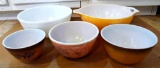 Pyrex mixing bowls and another. Largest Pyrex bowl has a daisy or sunflower pattern. Painted bowls