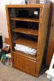 Storage cabinet with glass door has adjustable shelves and bottom storage. Unit measures approx. 4'