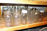 Shelf of quart narrow mouth canning jars with brands Ball, Kerr, Atlas and some with no brand names.
