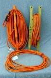 Three extension cords, two have cord holders. Coil on orange holder is about 15