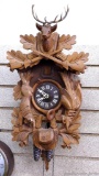 German cuckoo clock has stag head, rifles and game design. Carved case measures nearly 20