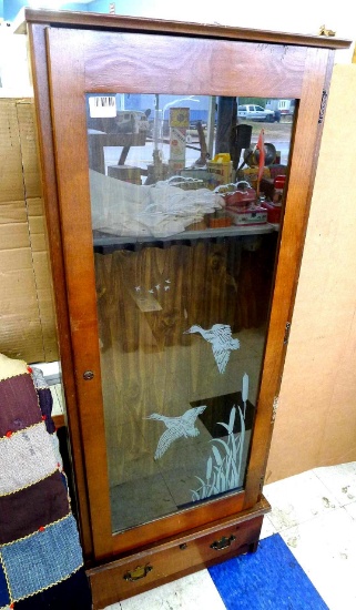 Glass front gun cabinet holds six rifles and has a drawer underneath for pistols, ammunition, or