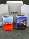 Two Zippo Cambridge lighters. Red lighter has spark; darker colored lighter still has original