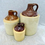 Three stoneware jugs, largest measuring 11'' tall. Largest jug has a repaired handle and a tight