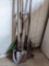 Two leaf rakes and three spade shovels.