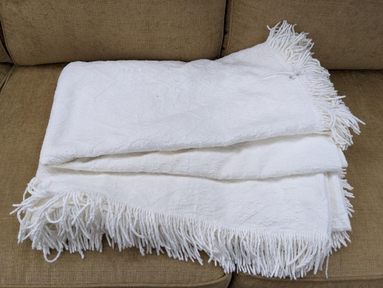 White or slightly cream colored matelasse bed spread is in good condition. Presumably a full/queen
