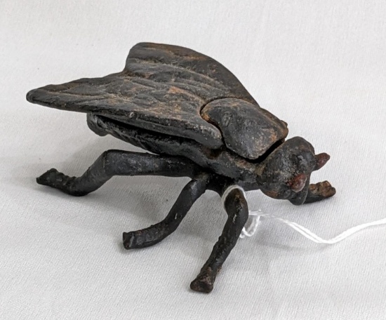 Cast iron fly with hinged wings as a lid to a hidden compartment in the body of fly; measures 3-3/4"