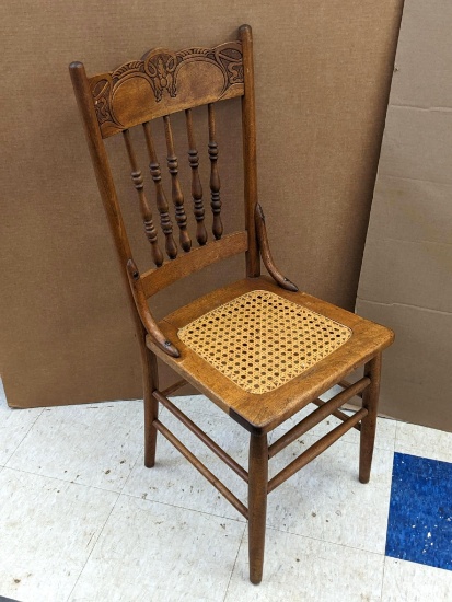 Nice sturdy wooden chair with ornate carving in the back, and a wicker seat. The chair is in overall