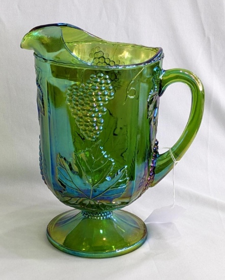 Green and blue carnival glass grape and grape leaf patterned footed pitcher is 10-1/2" tall. In good