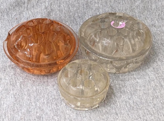 Pink Depression glass flower frog, plus two others 2-1/2" and 4" wide. Pink one about 4" wide.
