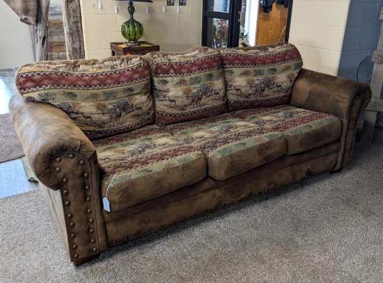 Northwoods themed sofa is in decent condition with one quarter-sized hole in one cushion. Measures