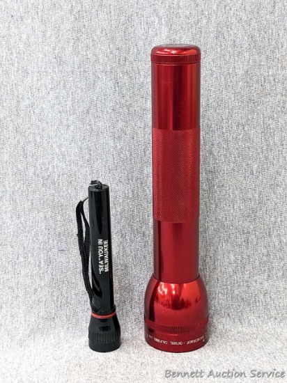 Red Mag-Lite flashlight and another flashlight that reads "Sea" You In Milwaukee. Smaller turns on,