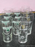 Guinness glasses - seven with green logo, four with gold logo.