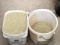 Two gallon bucket of grass seed; similar bucket about 1/4 full of grass seed.