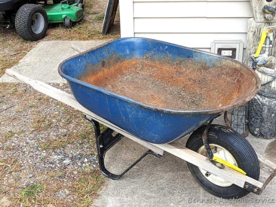 Blue wheelbarrow with a single wheel. Tire holds air, handles are solid, some rusting of the bucket