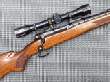 Winchester Model 70 Featherweight bolt action rifle chambered in .30-06 is topped with Weaver