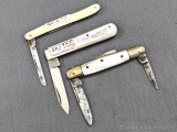 Three vintage folding pocket knives with ivory colored bone or similar handles, mother of pearl, and