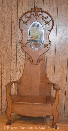 Oak hall tree with lift-lid seat, carved fish feet, oval beveled mirror, 4 coat/hat hooks, ornate