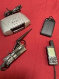 Grouping of 4 electronics, Clock radio, Magellan GPS 310, Ubiquitti unit, Nekteck Solar battery.