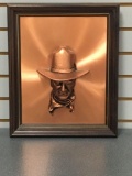 Copper colored bust of John Wayne in a frame