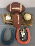 Group of two old time baseball gloves, one baseball and softball, to horseshoes, two footballs, one