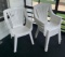 Group of four white plastic patio chairs