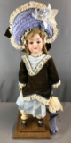 Antique doll on wooden base, bisque head, blue eyes