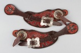 Ornate pair of two piece floral Straps with raised silver conchos and Clint Mortenson engraved sterl