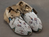 Pair of early full beaded Moccasins on natural tanned hide, multi-color beads, with crossed flags an