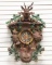 Carved Cuckoo Clock with stag crest has carved rifle, rabbit, grouse, calling horn and carry bag wit