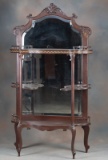Antique beveled glass mahogany Wall Curio, circa 1915-1920, with carved crest and full length bevele
