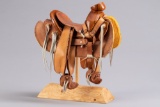 Well-made miniature leather Mexican Saddle with wooden tree on custom made wooden stand, measures ov