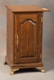 Custom oak Chair Side Stand with full length raised panel door, brass hardware and fancy brass feet.