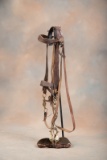 A vintage tooled Bridle complete with leather reins accompanied by a Hercules Bronze Bit with raised