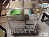 Chrome colored rolling storage cart with contents