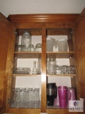 Contents of kitchen cabinet includes glass tumblers mugs canisters and pitchers