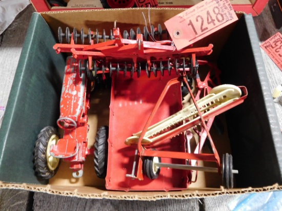 Well-used toy tractor, wagon, disc, plow, hay rake