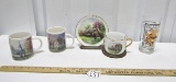 2 Thomas Kinkade Mugs; A Thomas Kinkade Mug, Saucer And Stand; And