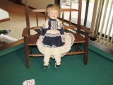Porcelain Doll Sitting On A Wood Bench W/ Cane Seat
