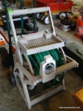 (G) GARDEN HOSE ON HOSE CADDY. IS IN GOOD CONDITION
