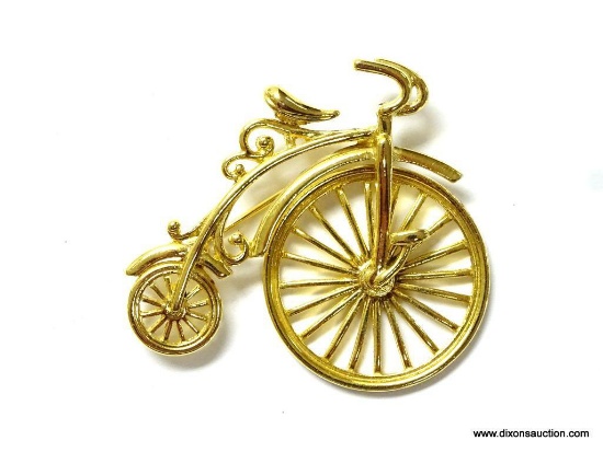 ANTIQUE BICYCLE THEMED GOLD TONE BROOCH/PIN. HAS LARGE MOVING FRONT WHEEL. 2" WIDE AND 1.75" TALL.
