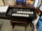 (ROW 1) TECHNICS ELECTRONIC ORGAN IN MAHOGANY CASE WITH MATCHING STOOL. HAS SHEET MUSIC STAND. THIS