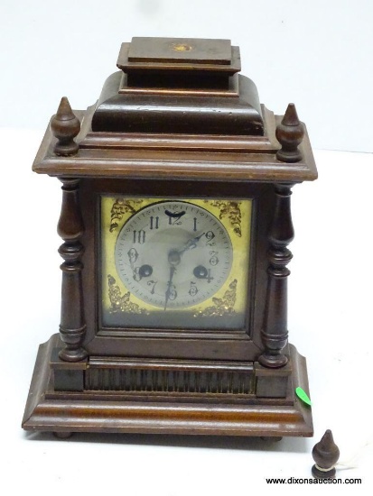 GERMAN MINI ONE-DAY SHELF CLOCK WITH FINIALS. BACK LEFT BUN FOOT NEEDS TO BE REPLACED AND TOP CENTER
