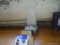 (LEFT SIDE WALL) MINI-IRONING BOARD WITH WHITE/BLUE COVER, BLUE BOX OF ASSORTED LIGHT BULBS, AND