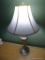 (BR3) TABLE LAMP; BRUSHED CHROME STAND WITH WHITE BELL OVAL LAMPSHADE. MEASURES 16