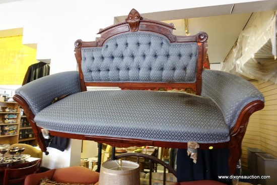 (UP) VINTAGE LOVESEAT; ELABORATE VICTORIAN WOOD DETAIL, TUFTED BACK, AND CASTER WHEELS HIGHLIGHT